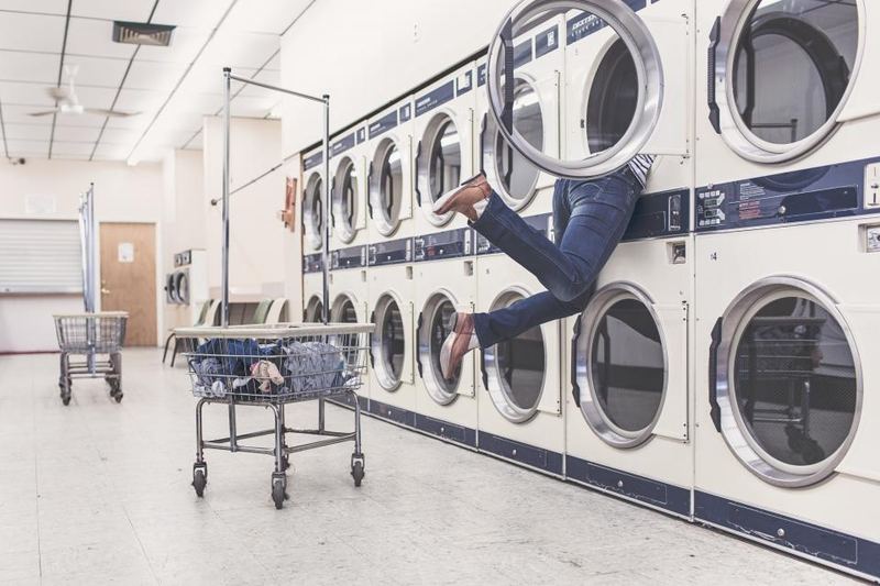 Someone searching inside a washing machine at a laundromat